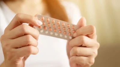 A woman holding a birth control pill in her hands.