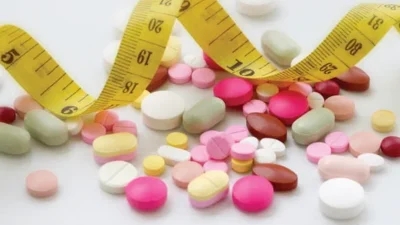 A measuring tape with weight loss pills and pills around it.