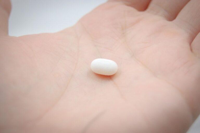 A single white Amycretin pill resting on the palm of a hand.