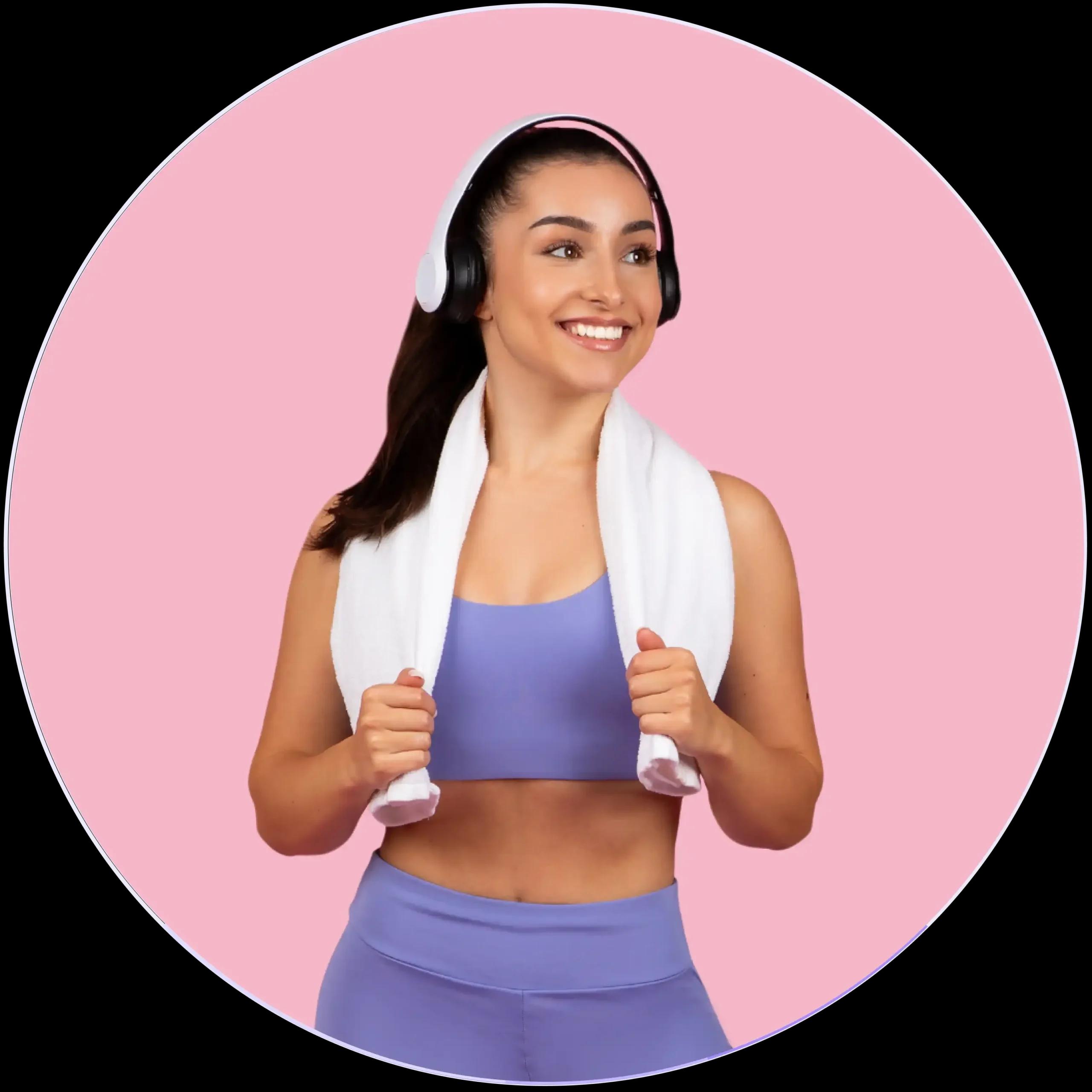 Woman in workout attire with headphones and towel, ready for fitness exercise.