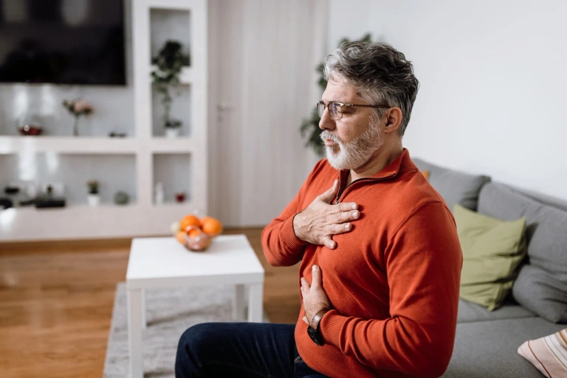 Elderly man holding his chest with a pained expression, questioning if unstable angina is a disability.