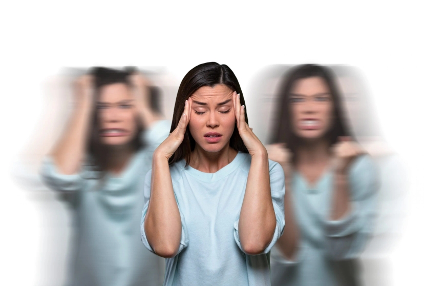 oman with a distressed expression, holding her head, with blurred images of herself in the background, illustrating the confusion and hallucinations associated with psychotic disorders.