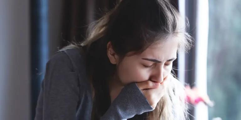 woman covering her mouth who is about to vomit