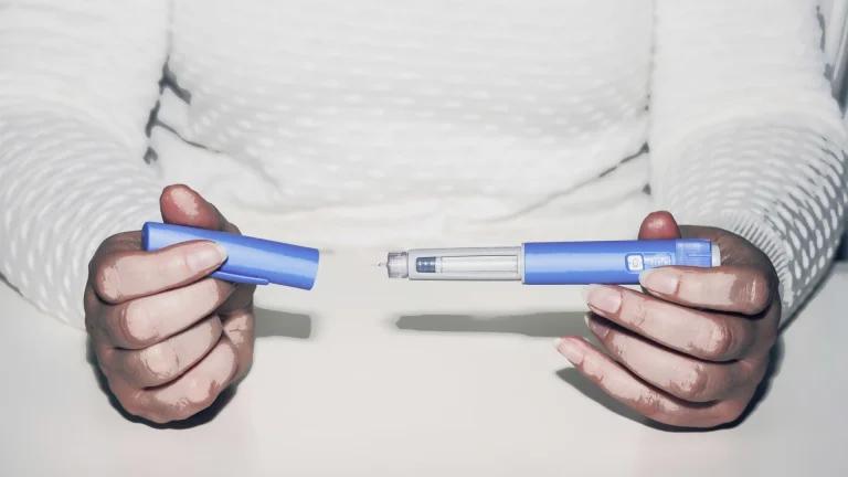 a person holding a ozmepic pen which can be used for wegiht loss and checking if it is the same as retatrutide